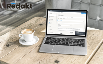 Laptop on a wooden desk with a screenshot of Redakt version 1.3 content editing experience